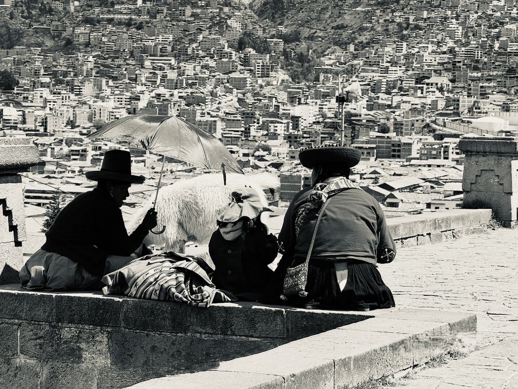 Cusco locals resting beside an alpaca overlooking the historic city of Cusco, Peru